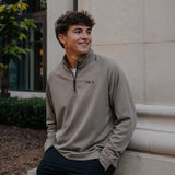 College-aged man wearing the Mushroom Cutter & Buck Adapt quarter-zip with black embroidered Pi Kappa Alpha Greek letters outdoors on campus.