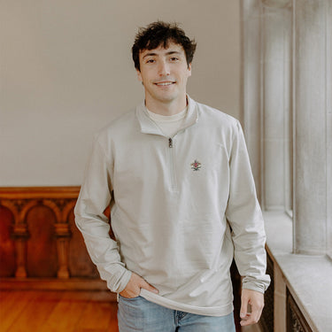 Male model wearing the smoke-colored Pi Kappa Alpha Embroidered Luxe Quarter Zip with crest embroidery, standing by a window in a formal setting.