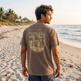 Model wearing the Surf Club Social T-shirt from the back while walking on a beach.