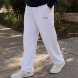 Close-up lifestyle photo of a college-aged male wearing ash gray classic sweatpants with a relaxed straight-leg fit, paired with a navy sweatshirt and white sneakers outdoors.