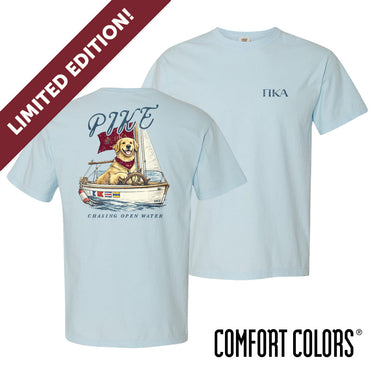 Light blue Comfort Colors t-shirt shown front and back; front features small Greek letters on the left chest, back displays a golden retriever sailing a boat with script text above and “Chasing Open Water” below.