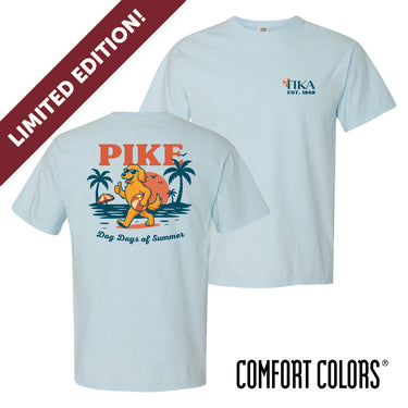 Light blue short sleeve Comfort Colors tee featuring Pi Kappa AlphaÕs golden retriever mascot on the back, lounging on a beach with palm trees and a sunset. Front chest print includes PIKE letters and a small beach ball detail.